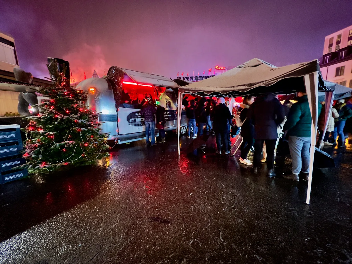 Man sieht einen Partybus am Freitagabend am Uster Märt. Leute stehen unter Zelten.